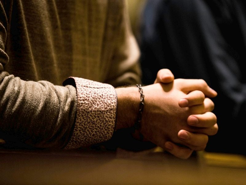 Deux personnes assises côte à côte, les mains jointes